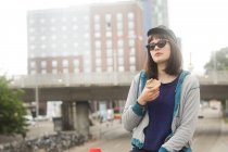 Porträt einer lächelnden Frau, die draußen steht und ein Stück Brot isst, Deutschland — Stockfoto