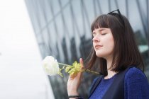 Ritratto di una donna sorridente che si trova all'aperto nella città con un fiore in mano, Germania — Foto stock