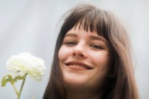 Retrato de una mujer sonriente sosteniendo una flor, Alemania - foto de stock