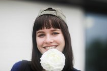 Retrato de uma mulher sorridente em um boné de beisebol segurando uma flor, Alemanha — Fotografia de Stock