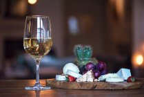 Склянка білого вина біля сирної дошки — стокове фото