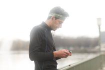 Portrait of a male jogger standing outdoors listening to music, Germany — Stock Photo