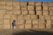 Mulher em pé na frente de uma pilha de fardos de feno em um campo, França — Fotografia de Stock
