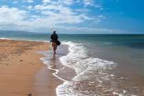 Retrato de um homem andando na praia carregando equipamentos de câmera, Havaí, EUA — Fotografia de Stock