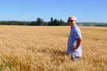Усміхнений чоловік стоїть на полі пшениці (Канада). — стокове фото