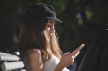 Девушка-подросток сидит на скамейке в парке, проверяет телефон, Аргентина — стоковое фото