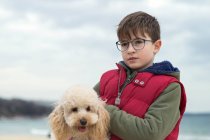 Мальчик, стоящий на пляже с собакой, Болгария — стоковое фото