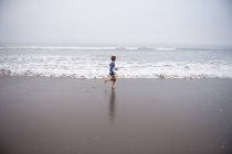 Menino correndo ao longo da praia, Califórnia, EUA — Fotografia de Stock
