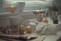 Золотые пасхальные яйца на кухонном столе с кружками, газетой и кофейником — стоковое фото