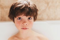 Retrato de un niño sentado en un baño de burbujas - foto de stock
