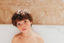 Retrato de un niño sentado en un baño de burbujas - foto de stock