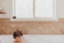 Portrait of a young boy sitting in a bubble bath — Stock Photo