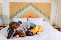 Madre e hijos abrazándose juntos en la cama - foto de stock