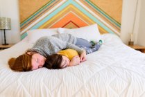 Mutter und Tochter schlafen und umarmen sich auf dem Bett — Stockfoto