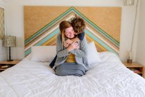 Mother and son lying and hugging together on bed — Stock Photo