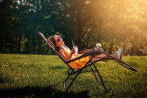 Щаслива дівчина сидить в саду з куркою на колінах — стокове фото