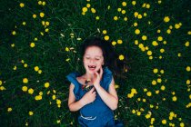 Vista aerea di una ragazza felice sdraiata in un prato con fiori di campo, Stati Uniti — Foto stock