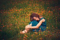 Ragazza felice seduta in un prato con fiori di campo, USA — Foto stock