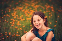 Happy girl sitting in a meadow with wildflowers, USA — Stock Photo