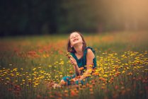 Щаслива дівчина, що сидить на лузі і збирає польові квіти (США). — стокове фото