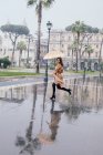 Femme courant à travers la ville sous la pluie, Rome, Latium, Italie — Photo de stock