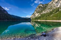 Mujer sentada junto al lago Braies tomando una foto, Tirol del Sur, Italia - foto de stock