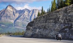 Dois motociclistas dirigindo através das montanhas rochosas, Canadá — Fotografia de Stock