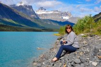 Woman sitting on rocks by Bow Lake, Banff National Park, Alberta, Canadá — Fotografia de Stock