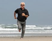 Uomo maturo che corre sulla spiaggia, Oregon, Stati Uniti d'America — Foto stock