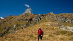 Посмішна жінка йде в гори з вершиною Маттергорн на віддалі, Церматт, Швейцарія. — стокове фото