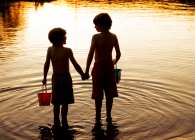 Silhueta de dois irmãos de pé em um lago de mãos dadas, Bedford, Halifax, Nova Escócia, Canadá — Fotografia de Stock