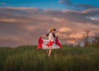 Chico corriendo por un campo sosteniendo una bandera canadiense, Bedford, Halifax, Nueva Escocia, Canadá - foto de stock