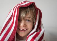 Retrato de un niño sonriente con toalla roja y blanca en la cabeza - foto de stock