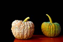 Two mouldy pumpkins on a red table — Stock Photo