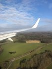 Aircraft wing and shadow of a plane  flying over rural landscape near Billund, Jutland, Denmark — Stock Photo