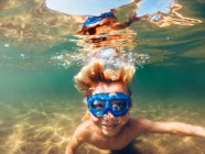 Garçon souriant nageant sous l'eau dans un lac, États-Unis — Photo de stock
