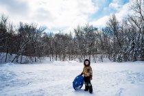 Ragazzo in piedi nella neve con la sua slitta, USA — Foto stock