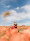 Porträt eines Jungen, der in einem Mohnfeld steht und eine Blume bläst, Antelope Valley California Poppy Reserve, Kalifornien, USA — Stockfoto