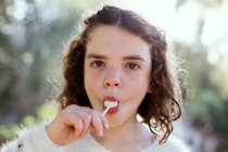 Retrato de una chica comiendo una piruleta sobre la naturaleza - foto de stock