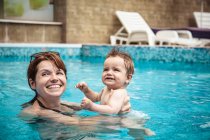 Mãe feliz nadando em uma piscina com seu filho bebê, Bulgária — Fotografia de Stock