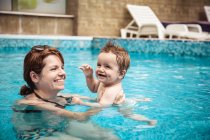 Glückliche Mutter beim Schwimmen in einem Schwimmbad mit ihrem kleinen Sohn, Bulgarien — Stockfoto