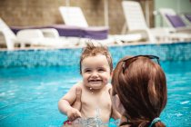 Вид сзади матери в бассейне, держащей своего маленького сына, Болгария — стоковое фото