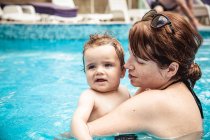 Madre feliz nadando en una piscina con su hijo pequeño, Bulgaria - foto de stock