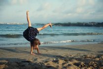 Девушка делает стойку на руках на пляже, Болгария — стоковое фото