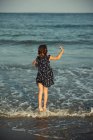 Vista trasera de una chica caminando en el océano surf, Bulgaria - foto de stock