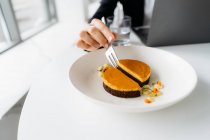 Close-up de uma mulher de negócios comendo mar buckthorn cheesecake enquanto trabalhava — Fotografia de Stock