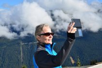 Portrait of a smiling woman taking a selfie in mountains, Whistler, British Columbia, Canada — Stock Photo
