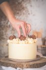 Frau dekoriert Buttercremetorte mit weißer Schokolade und Vollmilchschokolade — Stockfoto