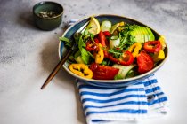 Salade de légumes santé avec aragula, avocat et graines de sésame sur fond béton avec espace de copie — Photo de stock