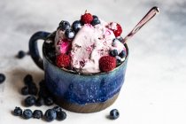 Фруктовый летний десерт с мороженым со свежими органическими ягодами черники подается в миске на каменном фоне с копировальным пространством — стоковое фото